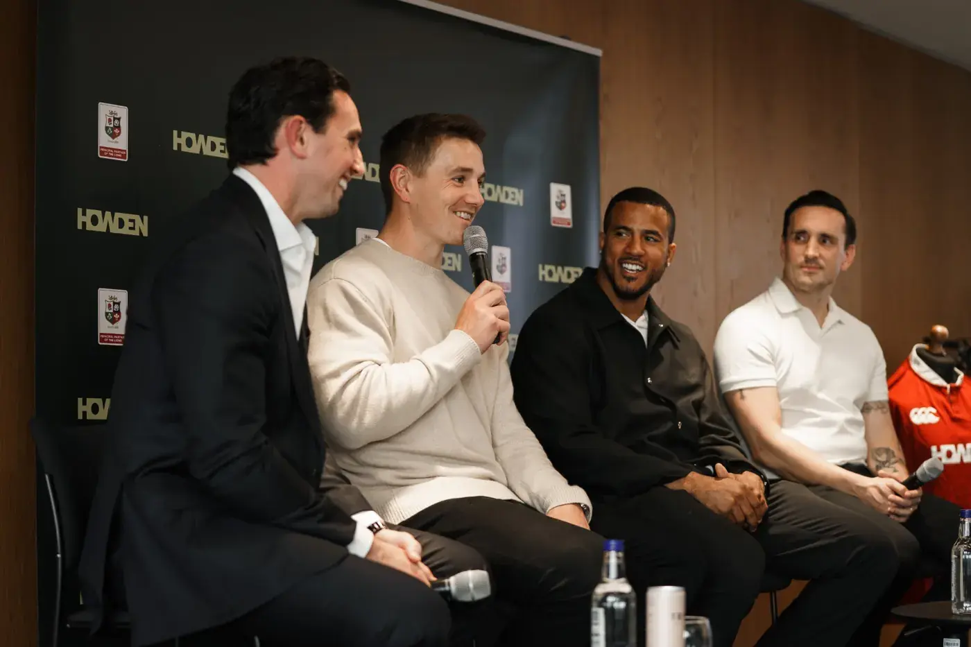Panel speakers in conversation in front of a Howden and British and Irish Lions backdrop