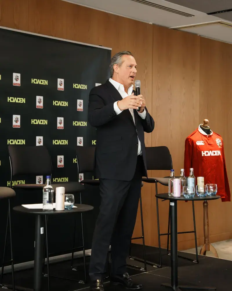 A speaker addressing Howden colleagues, beside a Howden British and Irish Lions shirt